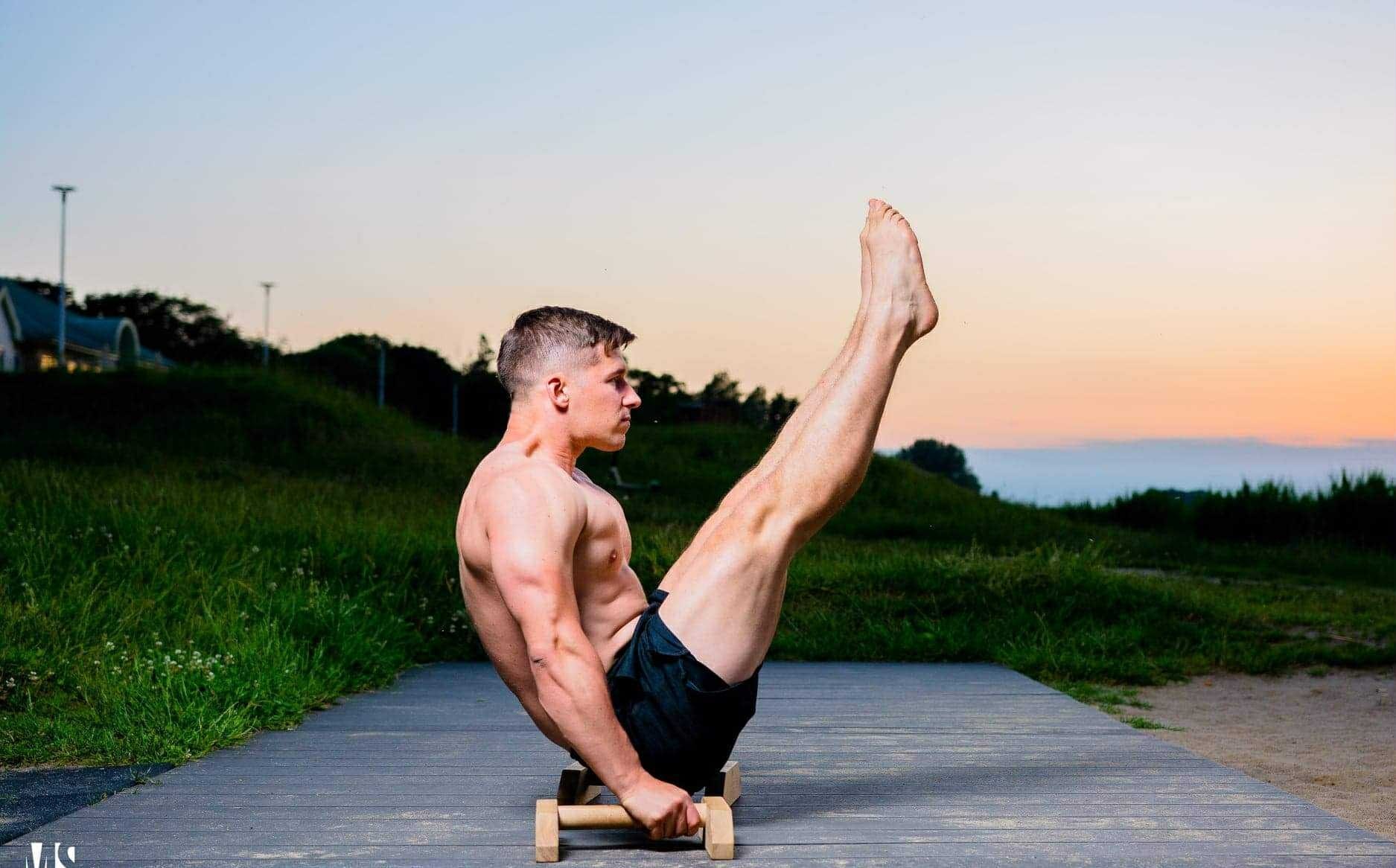 Zawodnik wykonujący L-sit na parallettes